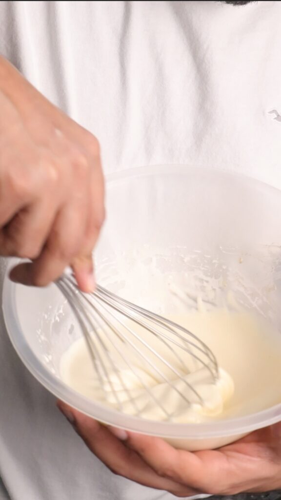 whipping cream in a mixing bowl with a hand whisk
