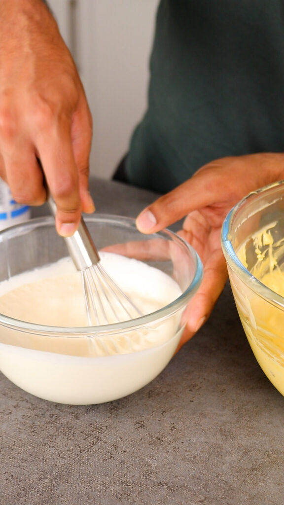 whisking double cream or heavy whipping cream in another mixing bowl