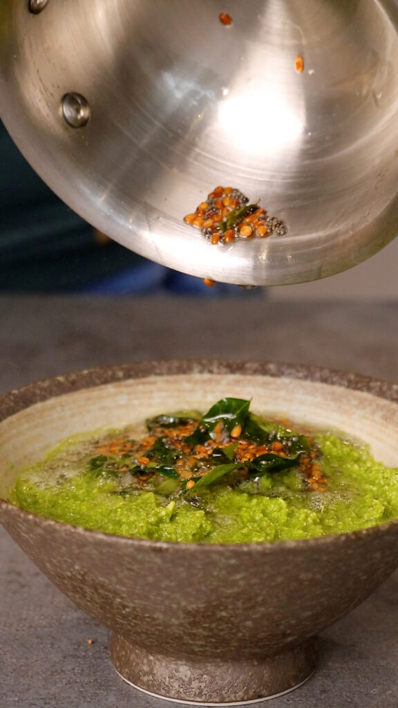 tempering being poured over the coconut and coriander chutney