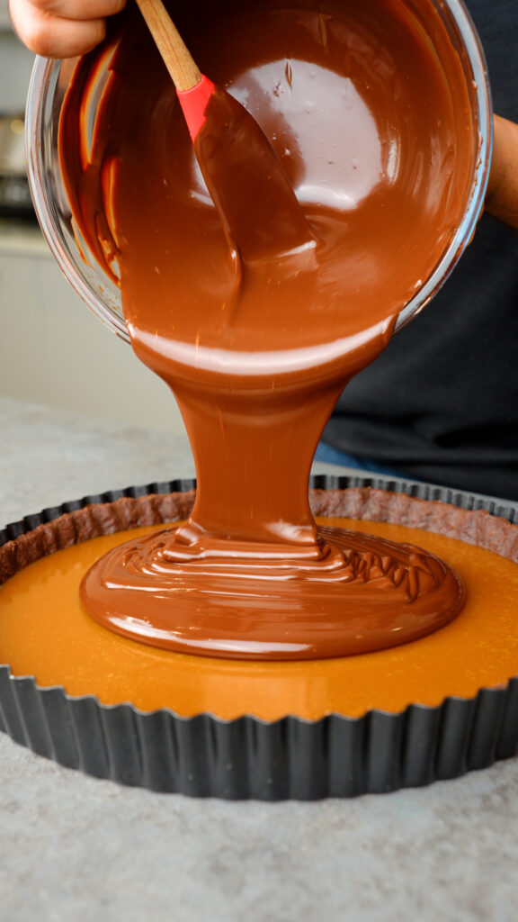 pour chocolate ganache over the caramel in the chocolate shortcrust pastry