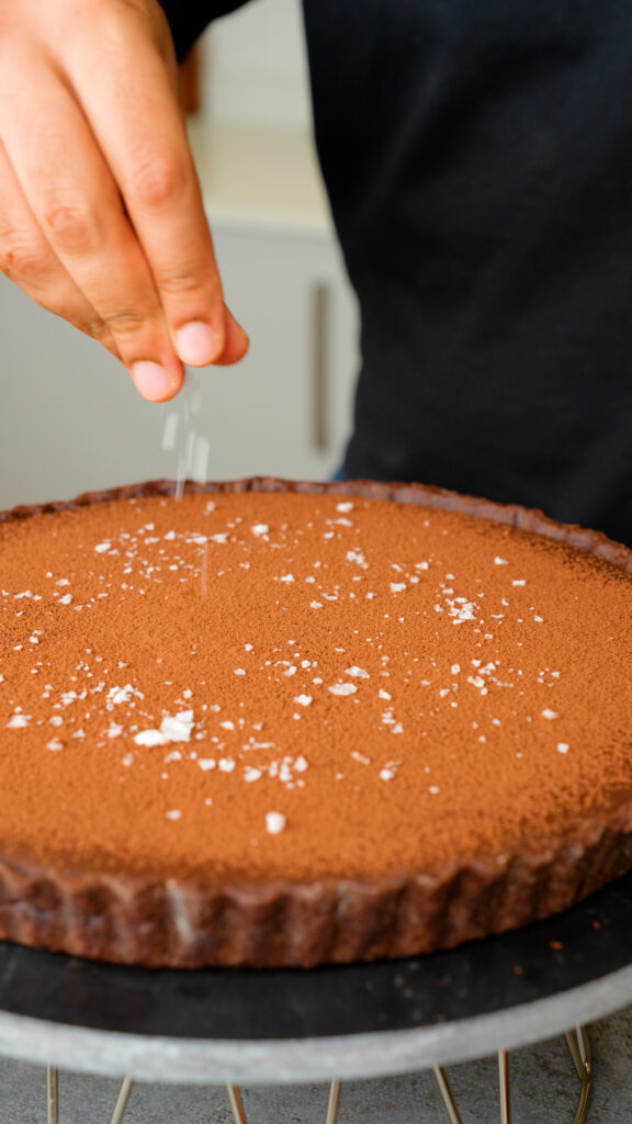 finish the chocolate and salted caramel tart with cocoa powder and flaky sea salt