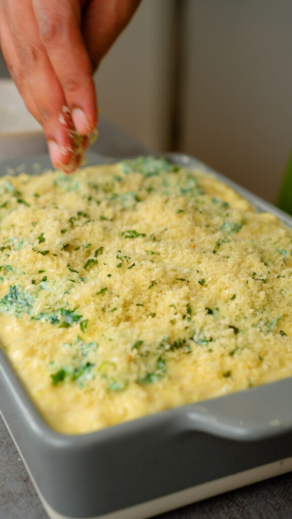 placing breadcrumbs on top of spinach and ricotta mac and cheese