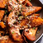 sesame potato wedges in a bowl topped with sauce and sesame seeds
