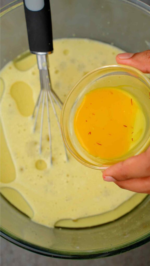 adding saffron milk to the mixing bowl