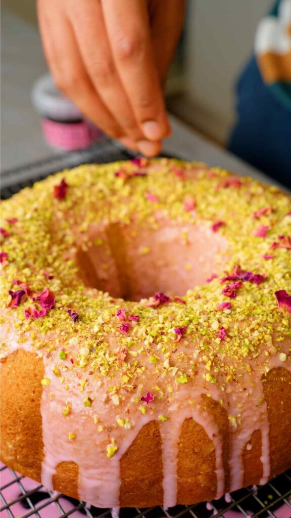 placing chopped pistachios and rose petals over the pistachio and rose bundt cake