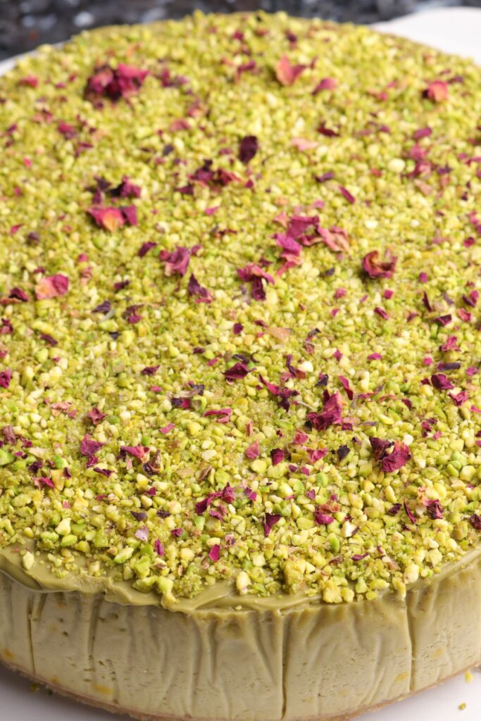 pistachios and rose petals on top of a pistachio cheesecake