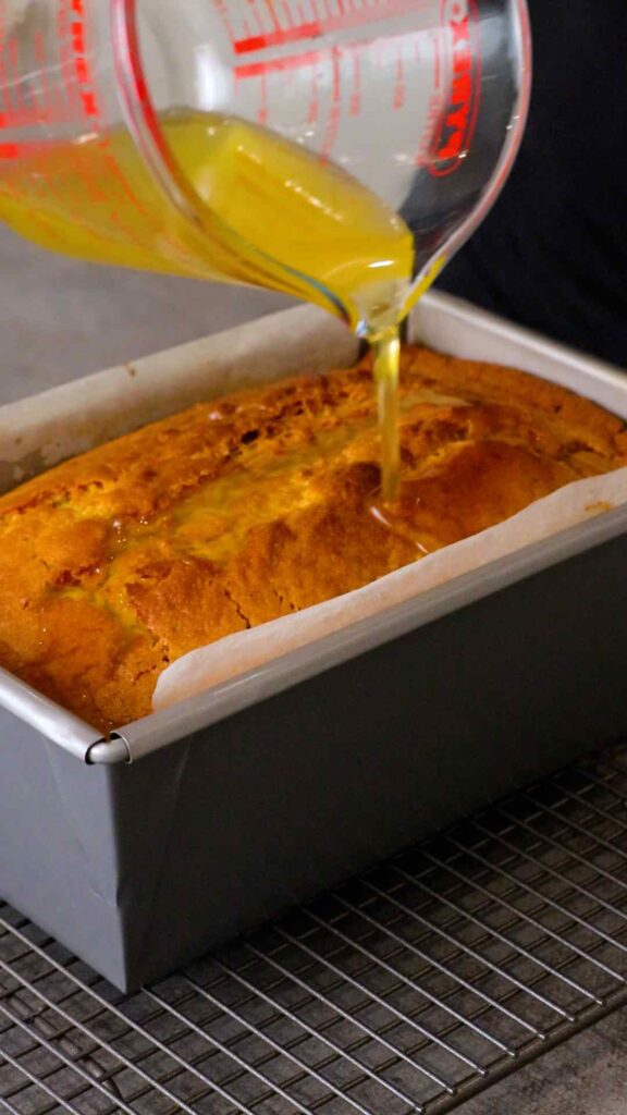 orange sugar syrup being poured over orange loaf