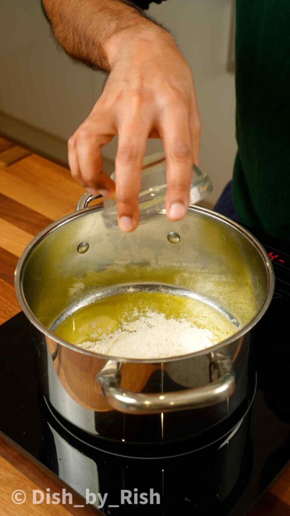 adding flour to melted butter in a pan