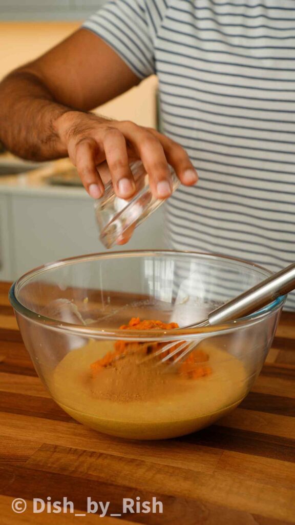 pumpkin purée and pumpkin spice being added to mixing bowl