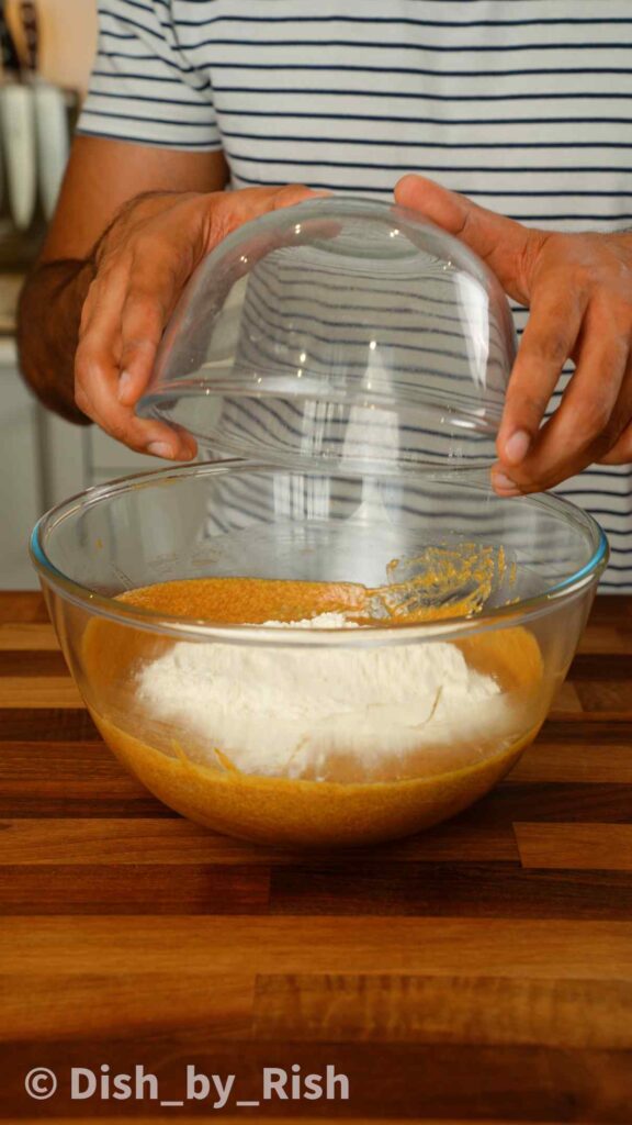adding flour and baking powder to wet pumpkin doughnut mix