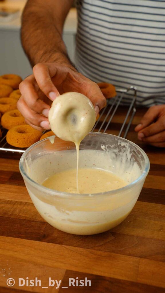 dunking pumpkin spice doughnuts in brown butter cream cheese glaze