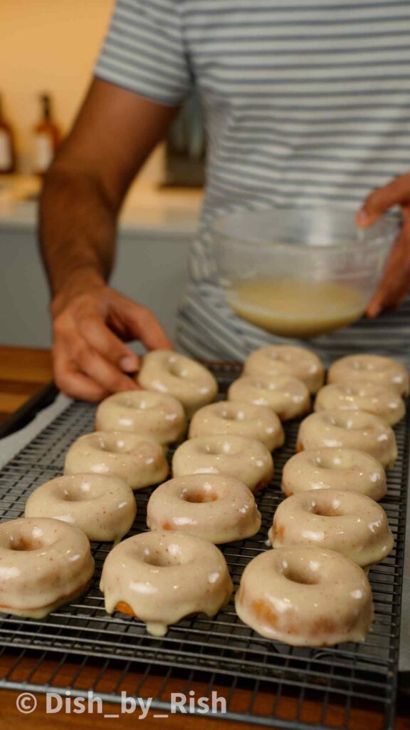 placing glazed doughnuts onto a wire rack
