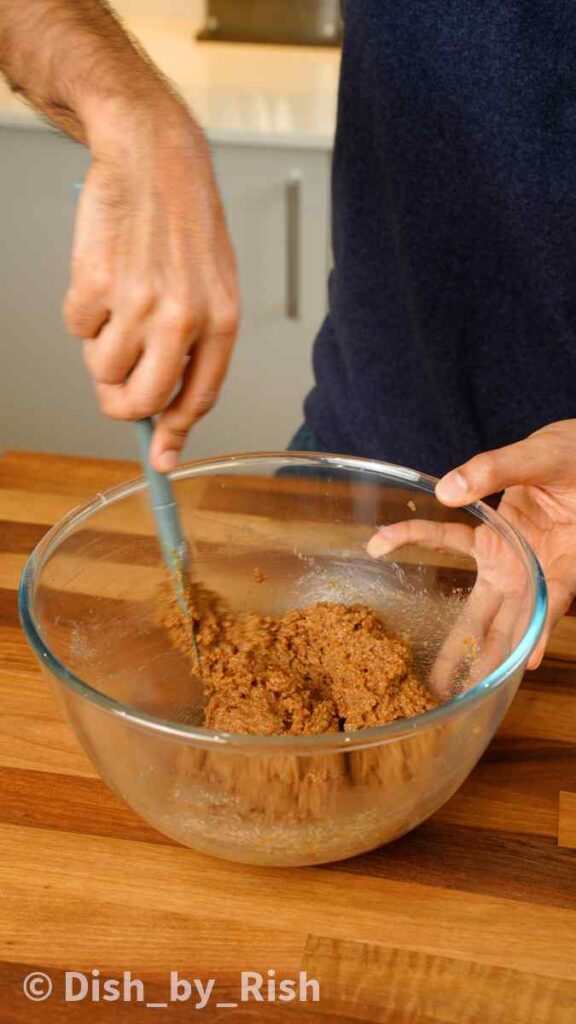 mixing butter and sugars together in a mixing bowl with a spatula
