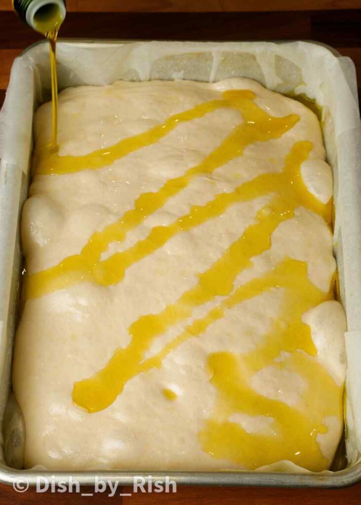 drizzling focaccia dough with olive oil