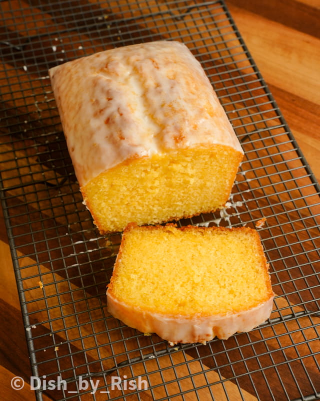 lemon drizzle loaf cake cut with a slice on a wire rack