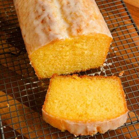 lemon drizzle loaf cake cut with a slice on a wire rack