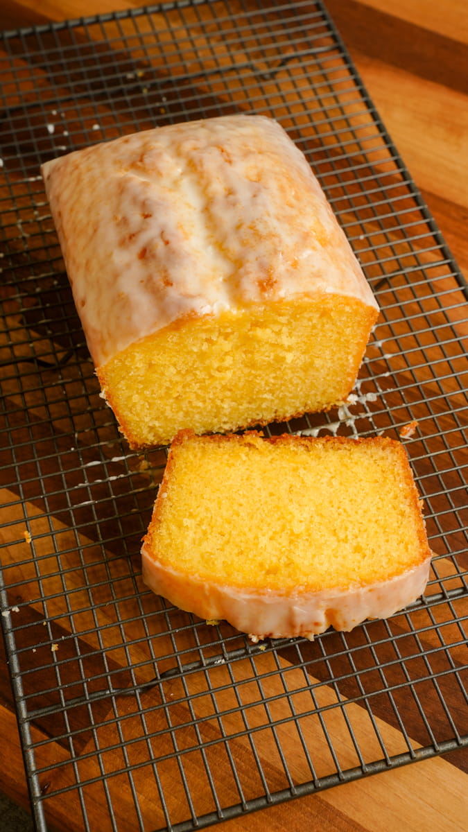 lemon drizzle loaf cake cut with a slice on a wire rack