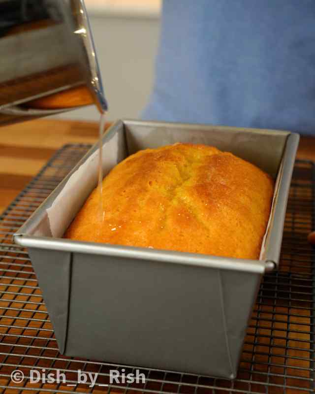 lemon syrup being poured on top of lemon loaf cake